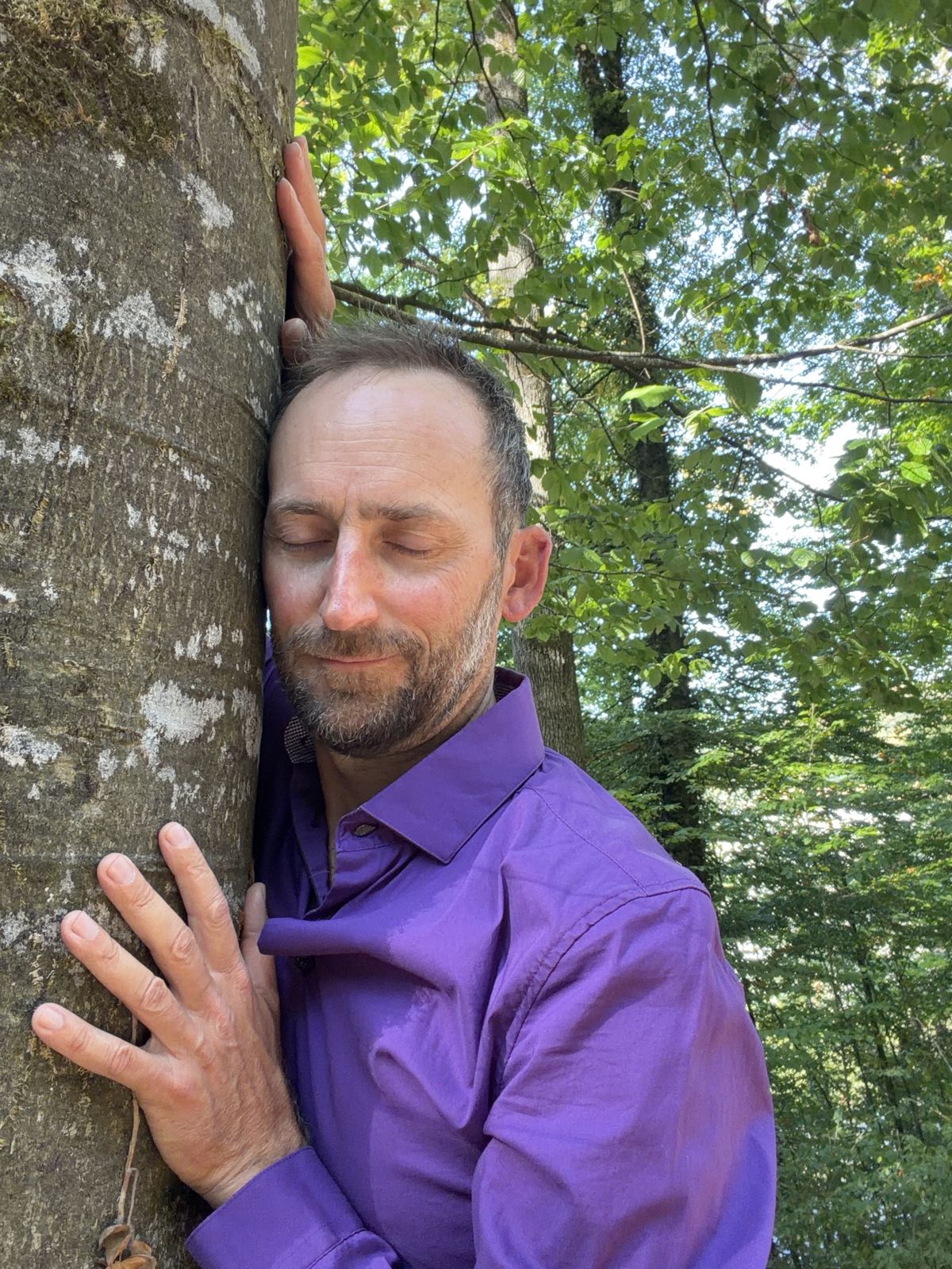 Noé Soleil mit geschlossenen Augen an einen Baum geschmiegt